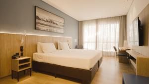 a bedroom with a bed and a desk and a television at Hotel Senac Ilha do Boi in Vitória