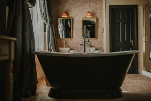 a bath tub in a bathroom with two mirrors at The Croft Hotel in Darlington