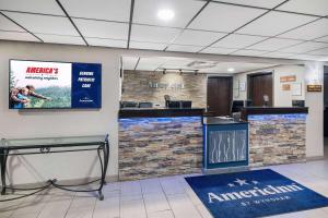an office with a lobby with a counter and a tv at AmericInn by Wyndham Plover Stevens Point in Plover