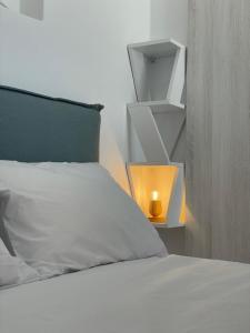 - une chambre avec un lit blanc et une lampe jaune dans l'établissement Th.èrοs - Sunset view apartment., à Parikia
