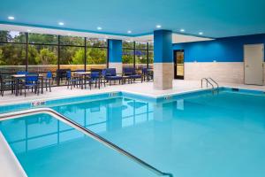 a swimming pool in a hotel with tables and chairs at Hampton Inn Towson Downtown in Towson
