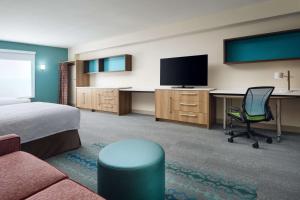 Habitación de hotel con cama y escritorio con TV. en Home2 Suites By Hilton Towson en Towson