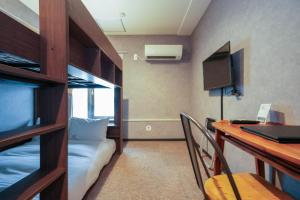 a room with a bunk bed and a desk with a laptop at Residence Hotel Stripe Sapporo in Sapporo