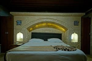 a bedroom with a large bed with a stone wall at Holiday Cave Hotel in Goreme