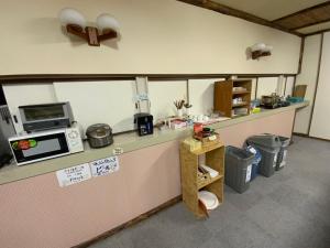 eine Küche mit einer Theke mit einer Mikrowelle und einigen Mülleimer in der Unterkunft Mashuko Youth Hostel in Teshikaga