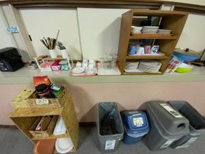 una habitación con un estante con platos y cubos de basura en Mashuko Youth Hostel, en Teshikaga