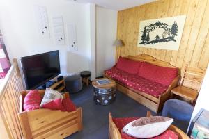 ein Wohnzimmer mit einem roten Sofa und einem TV in der Unterkunft Le Col Roulé in Valloire