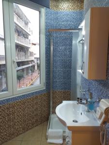 a bathroom with a sink and a window and a shower at CityZen Rooms Chios in Chios