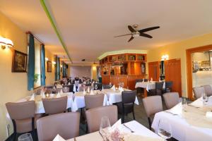 um restaurante com mesas e cadeiras brancas e uma ventoinha de tecto em Hotel Zum Goldenen Löwen em Peitz