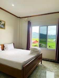 a bedroom with a bed and a large window at Hammer Guesthouse in Louang Namtha
