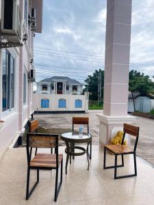 un patio con 3 sillas, una mesa y un edificio en Hammer Guesthouse, en Luang Namtha