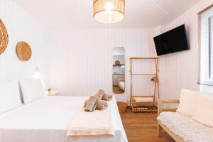 a white bedroom with a bed and a tv at Boho Central Suites in Thessaloniki