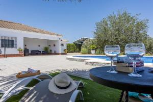 two glasses of wine sitting on a table by a pool at Casa Rural Manuel in La Puebla de Cazalla