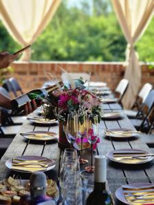 una larga mesa de madera con copas de vino y flores. en Vikendica Villa Ramona Banja Luka en Banja Luka