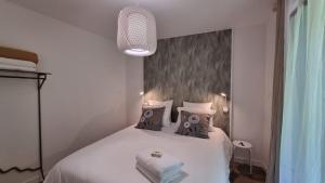 1 dormitorio con 1 cama con sábanas y almohadas blancas en La Crocherie : Gîte des Elfes - Free Wifi & Smart TV, en Beaumont-Pied-de-Boeuf