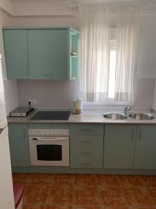 Una cocina con gabinetes blancos, un fregadero y una estufa. en Casa Mellis Aguamarga, en Agua Amarga