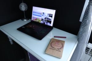 a laptop computer sitting on a desk with a notebook at The Dream Holiday House in Belicena