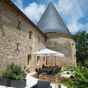 un edificio con una mesa y una sombrilla delante de él en 3 Gîtes avec piscine au Château de Charbogne 