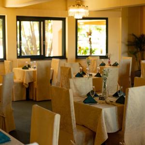 a restaurant with white tables and chairs and windows at Hotel Visconte D'Italia in Nova Hartz