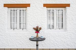 a table in front of a building with two windows at Sweet Home Madeira in Camacha
