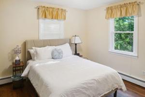 a bedroom with a large white bed with two windows at Private 4 bed home in 1 acre lot - 10 mins to IAD airport in Herndon