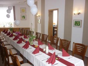 une longue table avec des serviettes rouges et des archets rouges dans l'établissement Hotel Waldhaus-Hutzelhöh, à Ruhla