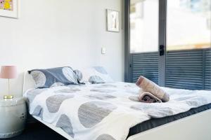 een bed met een wit en grijs dekbed en een raam bij New Comfy stylish Apt in Rhodes Next to train n shopping center in Sydney