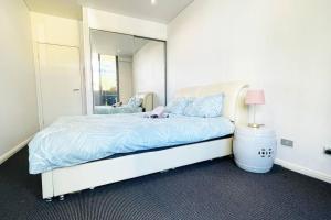 een slaapkamer met een bed en een grote spiegel bij New Comfy stylish Apt in Rhodes Next to train n shopping center in Sydney