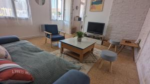 - un salon avec un canapé, une table et une télévision dans l'établissement Andernos-Maison de centre-ville avec jardin, à Andernos-les-Bains