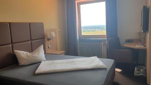 a bedroom with a bed with a pillow and a window at Restaurant und Hotel Alter Brunnen 