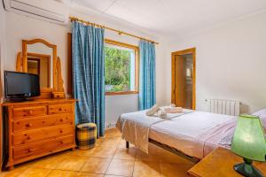 sypialnia z łóżkiem, telewizorem i komodą w obiekcie Casa Sergi mit kleinem Pool und Wifi w mieście Cala Llombards