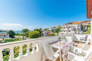 a balcony with a table and white chairs and a view at Apartment Dragan i Slavica in Lopar