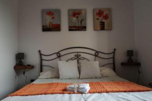 a bed with an orange blanket and three pictures on the wall at a casa di Sara in Sassari