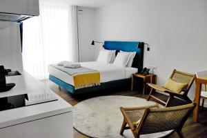 a bedroom with a bed and two chairs and a kitchen at Pêro Teive Bay Apartments Hotel in Ponta Delgada