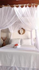 uma cama branca com um dossel com cortinas brancas em Machê Pousada & Boutique - A mais charmosa de Arraial D ajuda em Arraial d'Ajuda
