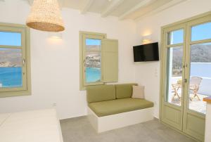 a room with a chair and a television and windows at ERISIMO SUITES in Aegiali