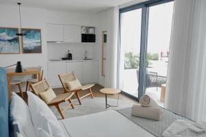 ein Wohnzimmer mit einem Sofa und Stühlen sowie eine Küche in der Unterkunft Pêro Teive Bay Apartments Hotel in Ponta Delgada