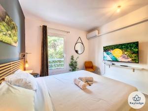 ein Schlafzimmer mit einem weißen Bett und einem TV an der Wand in der Unterkunft T3 - Tropical Lodge - 3 étoiles - 65m2 - Saint-Pierre in Saint-Pierre