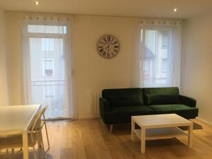 a living room with a green couch and a clock on the wall at Le Vauban - appartement 2 chambres, salon, cuisine équipée, parking et wifi gratuit in Mulhouse +10 photos