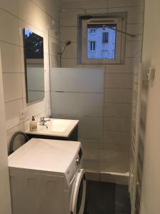 uma casa de banho branca com um lavatório e um espelho em Le Vauban - appartement 2 chambres, salon, cuisine équipée, parking et wifi gratuit em Mulhouse