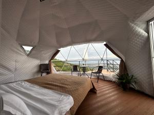 Signagi Glamping في سينغناغي: غرفة نوم بسرير ونافذة كبيرة