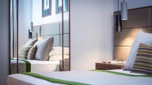 a hotel room with two beds and a mirror at Royal Neptun Hotel in Dubrovnik