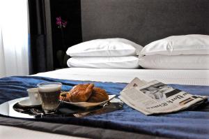 un vassoio per la colazione con caffè e croissant su un letto di Place 24 Suites & Wellness a Roma