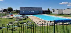 a swimming pool with tables and chairs next to a fence at Ashdale By Sea in Whitstable