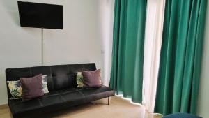 a black couch sitting in front of a window with green curtains at Paraiso Studio in Playa Paraiso +9 photos