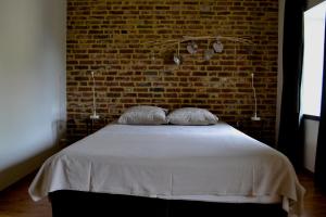 De Moolt Vakantiewoningen في Eckelrade: غرفة نوم بحائط من الطوب وسرير مع وسادتين
