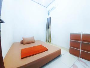 uma cama com uma almofada laranja num quarto em Baronda Guest House em Sorong