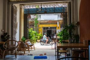 uma pessoa a andar de bicicleta numa sala com cadeiras e mesas em The Real Place Hostel em Battambang