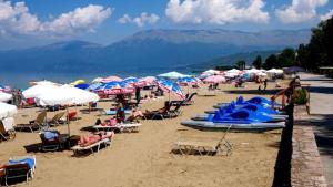 a group of people sitting on a beach with umbrellas at Very nice and romantic apartment in Pogradec