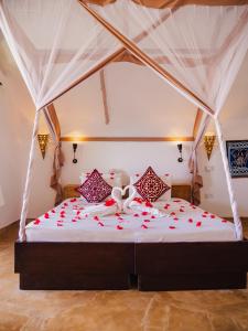 a bed with red rose petals on it at Sunshine Bay Hotel Zanzibar in Matemwe